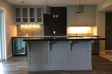 This is an example of a modern single-wall breakfast bar in Minneapolis with a built-in sink, shaker cabinets, grey cabinets, granite worktops, multi-coloured splashback, mosaic tiled splashback and ceramic flooring.