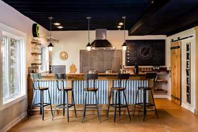 На фото: домашний бар в стиле лофт с мойкой, деревянной столешницей, серым фартуком и коричневым полом с