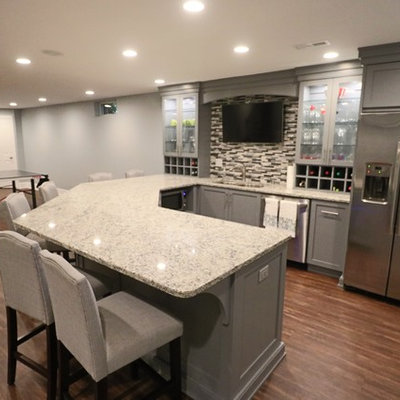 Seated home bar - huge contemporary u-shaped medium tone wood floor and brown floor seated home bar idea in Louisville with an undermount sink, glass-front cabinets, gray cabinets, granite countertops, multicolored backsplash, matchstick tile backsplash and gray countertops