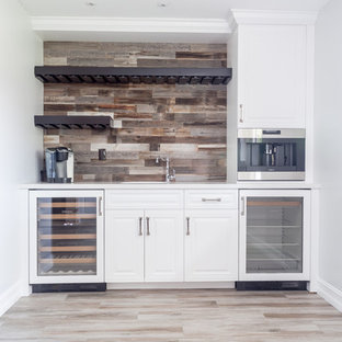 Immagine di un angolo bar con lavandino costiero di medie dimensioni con lavello sottopiano, ante con bugna sagomata, ante bianche, top in quarzite, paraspruzzi marrone, paraspruzzi in legno, pavimento con piastrelle in ceramica, pavimento marrone e top bianco