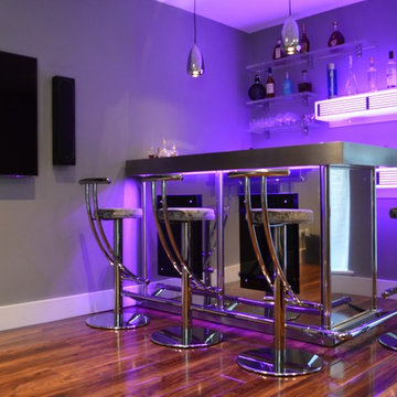 Bespoke corner bar in stainless steel with illuminated back bar shelving