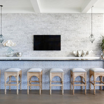 Example of a beach style medium tone wood floor seated home bar design in Orange County with black countertops