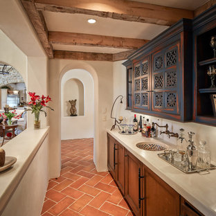 Idee per un angolo bar con lavandino mediterraneo con pavimento in terracotta, lavello sottopiano, ante con riquadro incassato, ante con finitura invecchiata e pavimento arancione