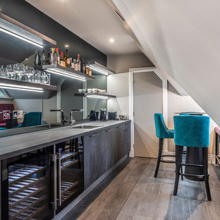 This is an example of a contemporary single-wall wet bar in Berkshire with a built-in sink, flat-panel cabinets, grey cabinets, mirror splashback, medium hardwood flooring, brown floors and grey worktops.