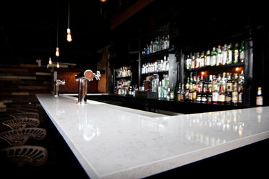 Diseño de bar en casa en U actual grande con armarios con paneles con relieve, puertas de armario negras y encimera de cuarzo compacto