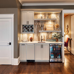 Foto di un angolo bar con lavandino rustico di medie dimensioni con lavello sottopiano, ante in stile shaker, ante bianche, paraspruzzi beige, pavimento in legno massello medio, pavimento marrone e top bianco