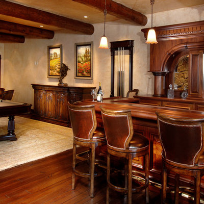 Example of a large mountain style dark wood floor and brown floor seated home bar design in Denver with an undermount sink, raised-panel cabinets, dark wood cabinets, copper countertops and mirror backsplash