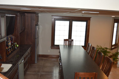 This is an example of a medium sized traditional galley breakfast bar in Kansas City with a submerged sink, raised-panel cabinets, dark wood cabinets, granite worktops, porcelain flooring and beige floors.