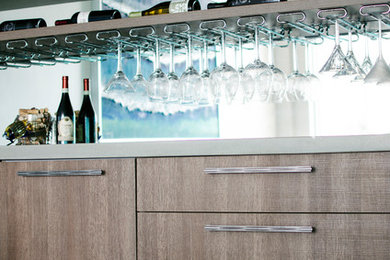 Photo of a contemporary single-wall wet bar with flat-panel cabinets, distressed cabinets and grey worktops.