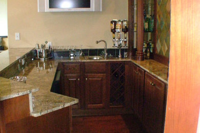 Small u-shaped seated home bar photo in Tampa with an undermount sink, raised-panel cabinets, granite countertops and dark wood cabinets