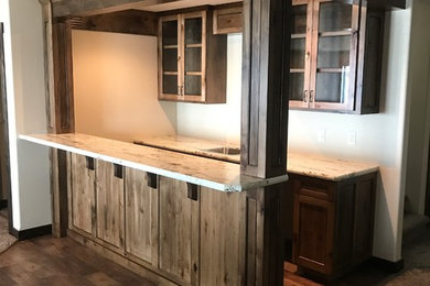 Example of a mid-sized mountain style galley dark wood floor and brown floor wet bar design in Other with a drop-in sink, recessed-panel cabinets, dark wood cabinets and granite countertops