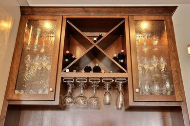 Example of a small arts and crafts single-wall wet bar design in Other with glass-front cabinets, medium tone wood cabinets, brown backsplash and wood backsplash
