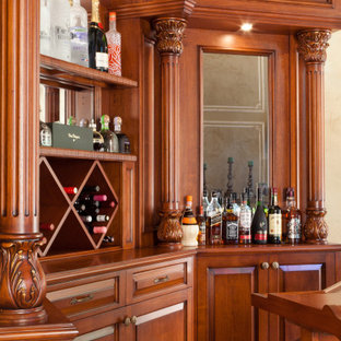 Idee per un bancone bar classico di medie dimensioni con nessun lavello, ante con bugna sagomata, ante in legno scuro, top in legno, pavimento in laminato e pavimento giallo