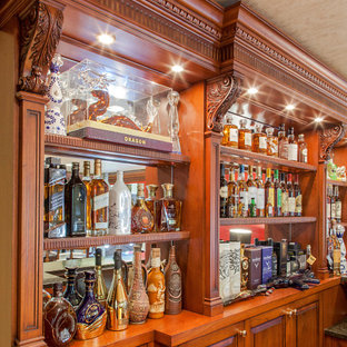 Esempio di un angolo bar con lavandino tradizionale di medie dimensioni con nessun lavello, ante con bugna sagomata, ante in legno scuro, top in granito, paraspruzzi grigio, paraspruzzi a specchio, pavimento in laminato, pavimento giallo e top grigio