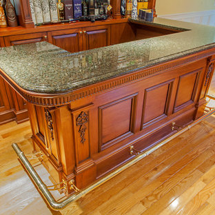 Immagine di un angolo bar con lavandino classico di medie dimensioni con nessun lavello, ante con bugna sagomata, ante in legno scuro, top in granito, paraspruzzi grigio, paraspruzzi a specchio, pavimento in laminato, pavimento giallo e top grigio