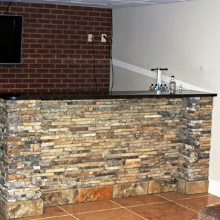 Idee per un piccolo angolo bar con lavandino industriale con lavello da incasso, ante con riquadro incassato, top in granito, paraspruzzi rosso, paraspruzzi in mattoni, pavimento in gres porcellanato, pavimento arancione e top nero