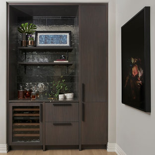 Foto de bar en casa lineal, actual, con armarios con paneles lisos, puertas de armario de madera en tonos medios, salpicadero negro, suelo de madera en tonos medios y suelo beige