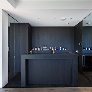 Photo of a modern home bar in Sydney with flat-panel cabinets, dark wood cabinets, black floor and black benchtop.