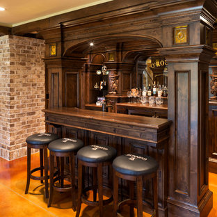 Esempio di un grande bancone bar classico con pavimento in cemento, ante con riquadro incassato, ante in legno bruno, top in legno, pavimento arancione, paraspruzzi a specchio e top marrone