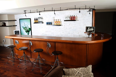 Modelo de bar en casa con barra de bar de tamaño medio con encimera de madera y suelo de madera oscura
