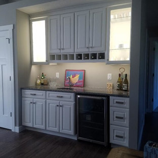 Mid-sized cottage single-wall laminate floor and brown floor wet bar photo in Other with an undermount sink, raised-panel cabinets, white cabinets and granite countertops