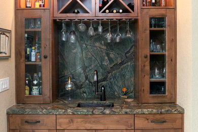 Wet bar - small rustic single-wall carpeted wet bar idea in Seattle with an undermount sink, raised-panel cabinets, medium tone wood cabinets, granite countertops, multicolored backsplash and stone slab backsplash
