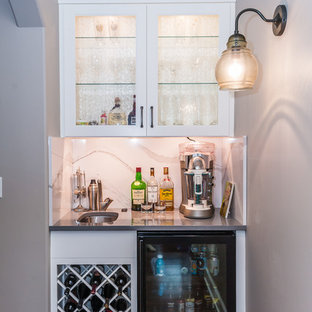 Immagine di un piccolo angolo bar con lavandino classico con lavello sottopiano, ante di vetro, ante bianche, top in superficie solida, paraspruzzi bianco, paraspruzzi in lastra di pietra, parquet scuro e pavimento marrone