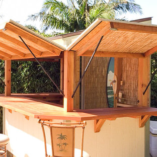 Immagine di un piccolo bancone bar tropicale con top in legno, paraspruzzi marrone, paraspruzzi in legno, pavimento in cemento e pavimento grigio