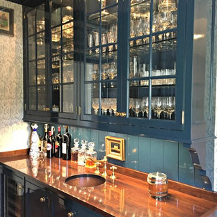 Imagen de bar en casa con fregadero lineal, tradicional, de tamaño medio, con fregadero bajoencimera, armarios tipo vitrina, puertas de armario azules, encimera de madera, salpicadero azul, suelo de madera oscura y encimeras marrones