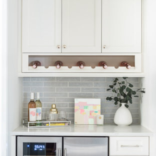 Idées déco pour un petit bar de salon linéaire classique avec aucun évier ou lavabo, un placard à porte shaker, des portes de placard blanches, un plan de travail en quartz modifié, une crédence grise, une crédence en carreau de porcelaine, un sol en bois brun, un sol marron et un plan de travail blanc.