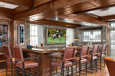 Large elegant u-shaped medium tone wood floor and brown floor seated home bar photo in New York with wood countertops and brown countertops