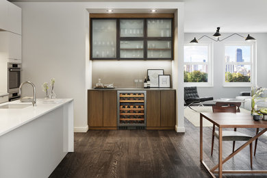 Example of a large trendy single-wall dark wood floor and brown floor wet bar design in Miami with an undermount sink, flat-panel cabinets, solid surface countertops and dark wood cabinets
