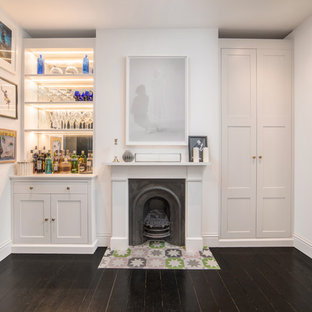 Small traditional single-wall home bar in London with no sink, shaker cabinets, grey cabinets, mirror splashback, dark hardwood flooring and grey worktops.