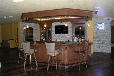 Inspiration for a large timeless single-wall dark wood floor and brown floor seated home bar remodel in Other with gray backsplash, brick backsplash, raised-panel cabinets, medium tone wood cabinets and granite countertops