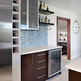 Inspiration pour un bar de salon linéaire minimaliste de taille moyenne avec un placard à porte plane, des portes de placard en bois sombre, un plan de travail en quartz modifié, une crédence bleue, une crédence en carreau de verre et un sol en carrelage de céramique.