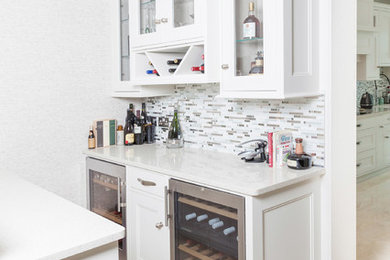 Klassische Hausbar mit weißen Schränken, Quarzit-Arbeitsplatte und Rückwand aus Keramikfliesen in Sonstige