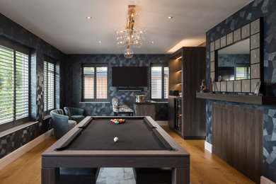 Imagen de bar en casa contemporáneo grande con puertas de armario de madera en tonos medios, encimera de acrílico, suelo de madera clara y encimeras negras