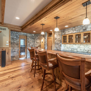 Immagine di un bancone bar american style di medie dimensioni con lavello sottopiano, ante in stile shaker, ante con finitura invecchiata, top in legno, paraspruzzi grigio, paraspruzzi in pietra calcarea, parquet chiaro, pavimento giallo e top marrone