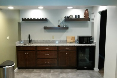 Example of a small minimalist single-wall gray floor wet bar design in Philadelphia with an undermount sink, recessed-panel cabinets, dark wood cabinets, granite countertops, multicolored backsplash, stone slab backsplash and multicolored countertops