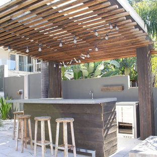Immagine di un piccolo bancone bar costiero con lavello sottopiano, ante in legno bruno, top in cemento e paraspruzzi grigio