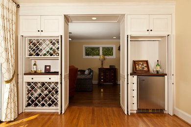 Diseño de bar en casa tradicional con armarios con paneles empotrados, puertas de armario blancas, encimera de madera y suelo de madera en tonos medios