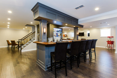 Example of a large trendy u-shaped dark wood floor and brown floor seated home bar design in Philadelphia with an undermount sink, recessed-panel cabinets, black cabinets, wood countertops, white backsplash, stone tile backsplash and brown countertops