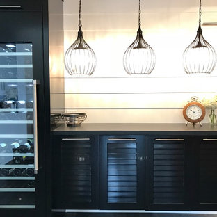 Ispirazione per un angolo bar senza lavandino country di medie dimensioni con parquet scuro, pavimento nero, nessun lavello, ante a persiana, ante nere, top in quarzo composito, paraspruzzi bianco, paraspruzzi in legno e top nero