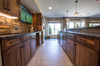 Example of a large mountain style galley ceramic tile seated home bar design in Other with an undermount sink, shaker cabinets, medium tone wood cabinets, solid surface countertops, multicolored backsplash and stone tile backsplash