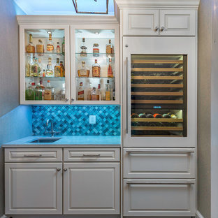 Esempio di un piccolo angolo bar con lavandino tradizionale con lavello sottopiano, ante con bugna sagomata, ante bianche, top in quarzo composito, paraspruzzi blu, paraspruzzi con piastrelle di vetro, pavimento in legno massello medio, pavimento marrone e top bianco
