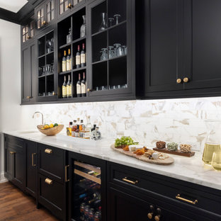 Foto de bar en casa con fregadero lineal, de estilo de casa de campo, grande, con fregadero bajoencimera, armarios estilo shaker, puertas de armario negras, salpicadero multicolor, suelo de madera en tonos medios, suelo marrón y encimeras blancas