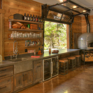 Example of a mountain style single-wall concrete floor and brown floor home bar design in Minneapolis with an integrated sink, shaker cabinets, dark wood cabinets and gray countertops