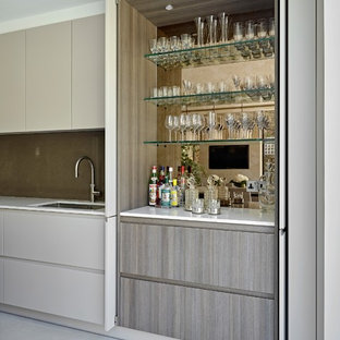 Photo of a contemporary single-wall wet bar in London with a submerged sink, flat-panel cabinets, grey cabinets, mirror splashback, grey floors and white worktops.