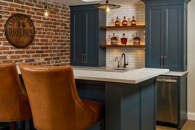 Example of a mid-sized classic galley brown floor seated home bar design in Minneapolis with shaker cabinets, blue cabinets, white backsplash, subway tile backsplash, an undermount sink and white countertops