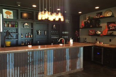 Example of an urban concrete floor home bar design in Portland with black cabinets, wood countertops and brown countertops